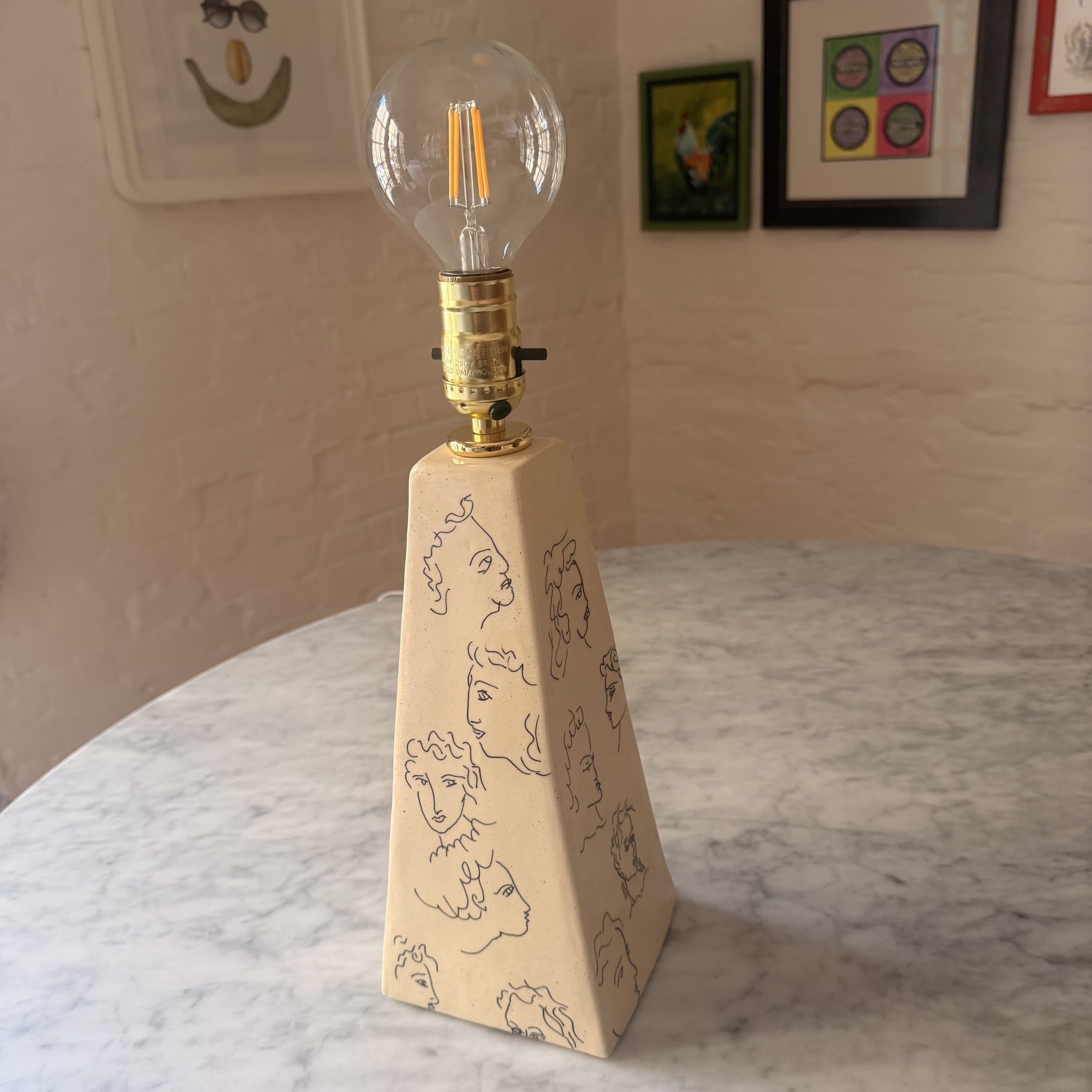 A hand-built ceramic pyramid lamp sitting on a marble surface.