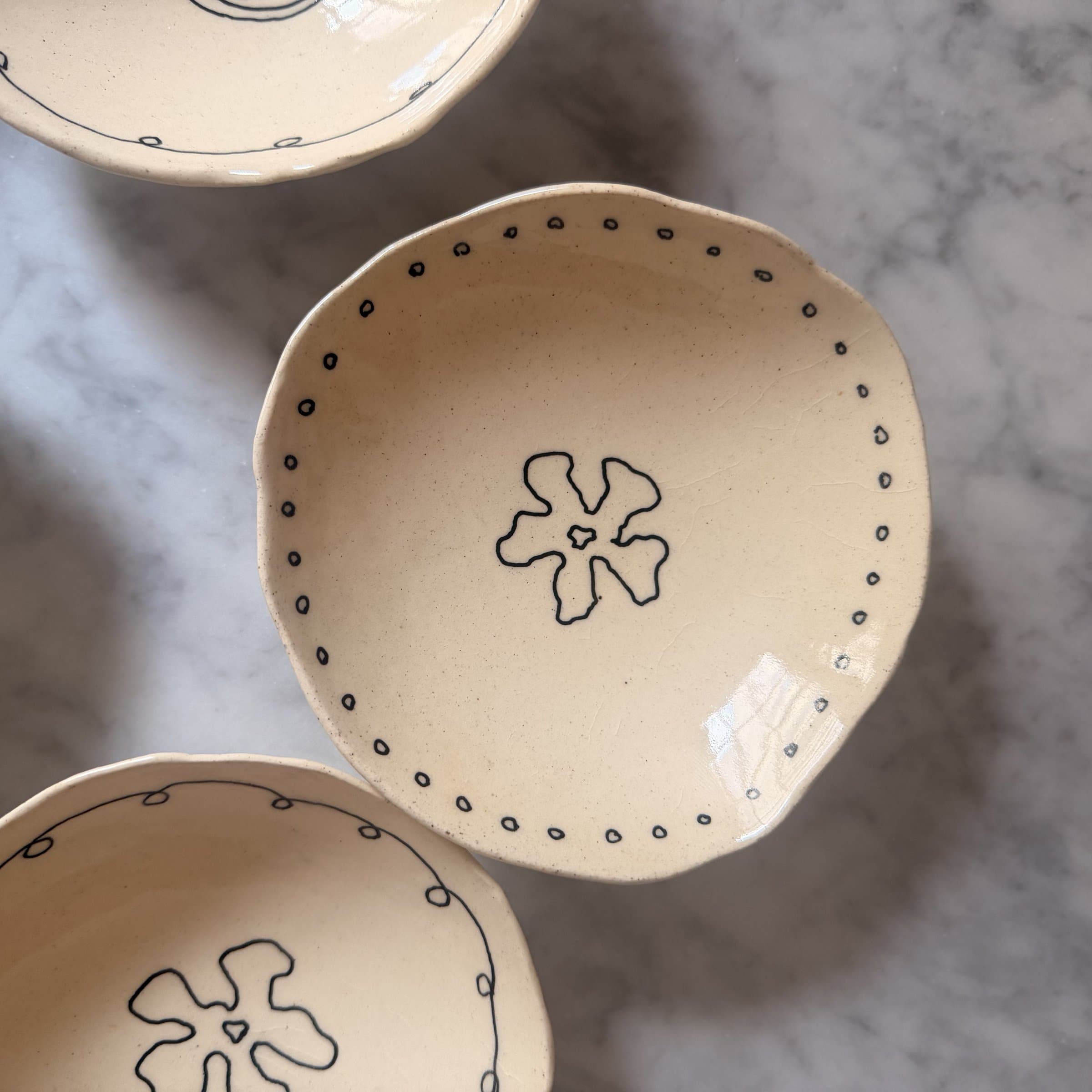 A single scalloped bowl with a small flower medallion and a dotted scribble border.