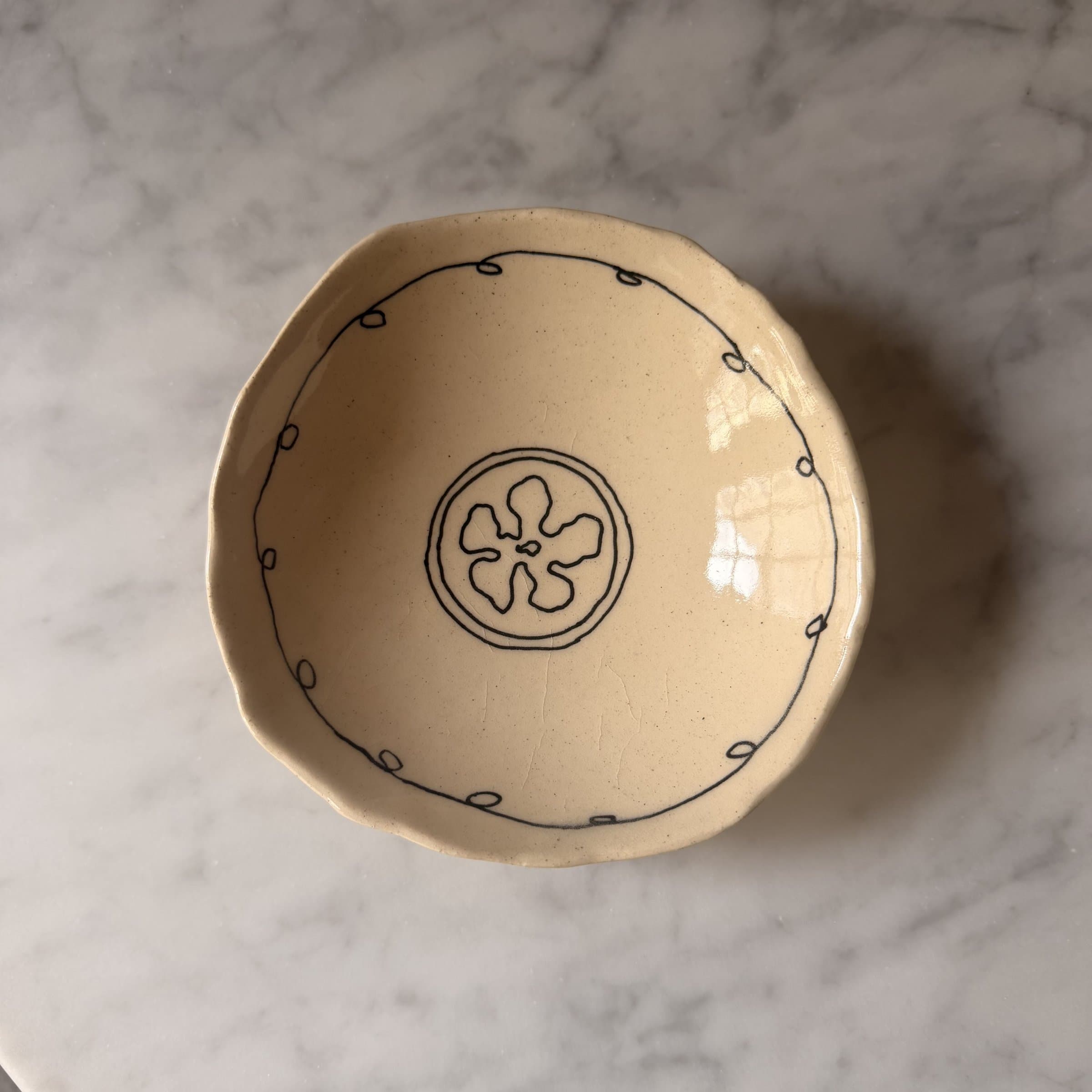 A single scalloped bowl with a flower medallion in the center, hand-drawn loop border.